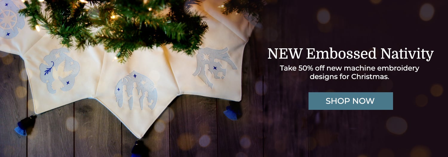 New Embossed Nativity - 50% off - image features: nativity designs on white tree skirt with blue tassels under christmas tree 