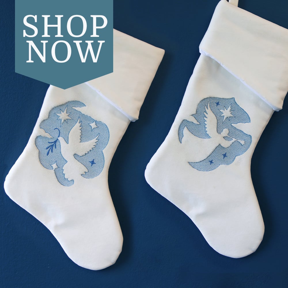 Embossed nativity designs - image features: dove and angel design on white stocking on blue wall 